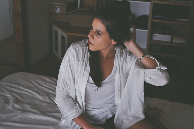 Žena v bielom oblečení sedí na posteli.jpg